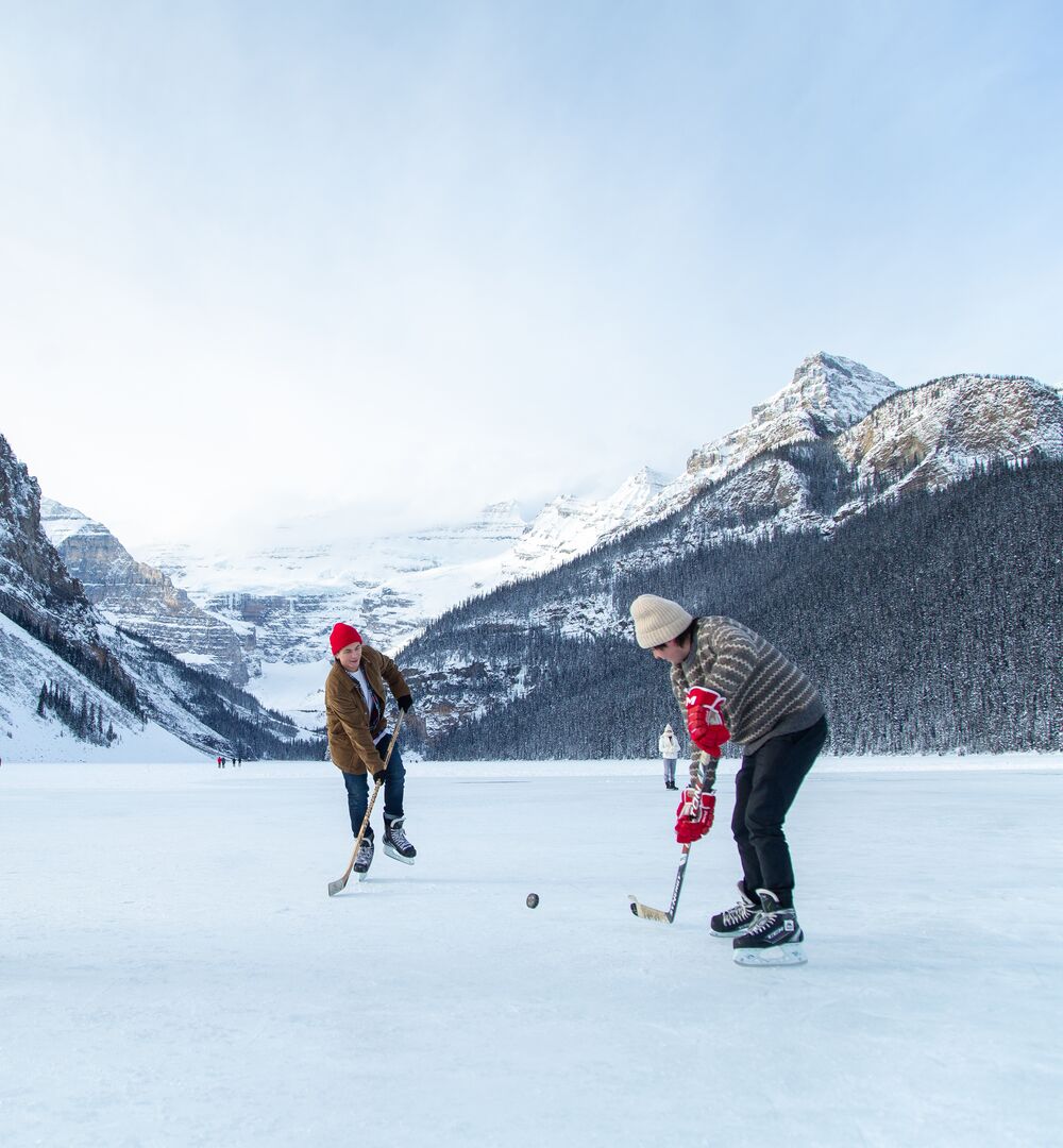 A group of friends playing shinny on Lake Louise in the winter in Banff National Park