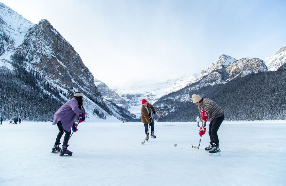 A group of friends playing shinny on Lake Louise in the winter in Banff National Park