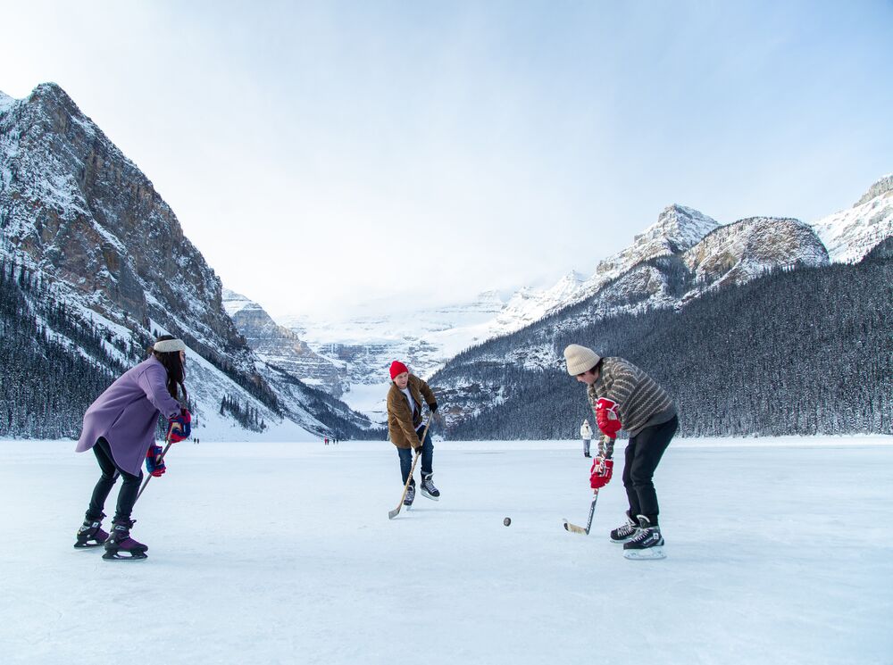 Three people playing hockey on Lake Louise in Banff National Park