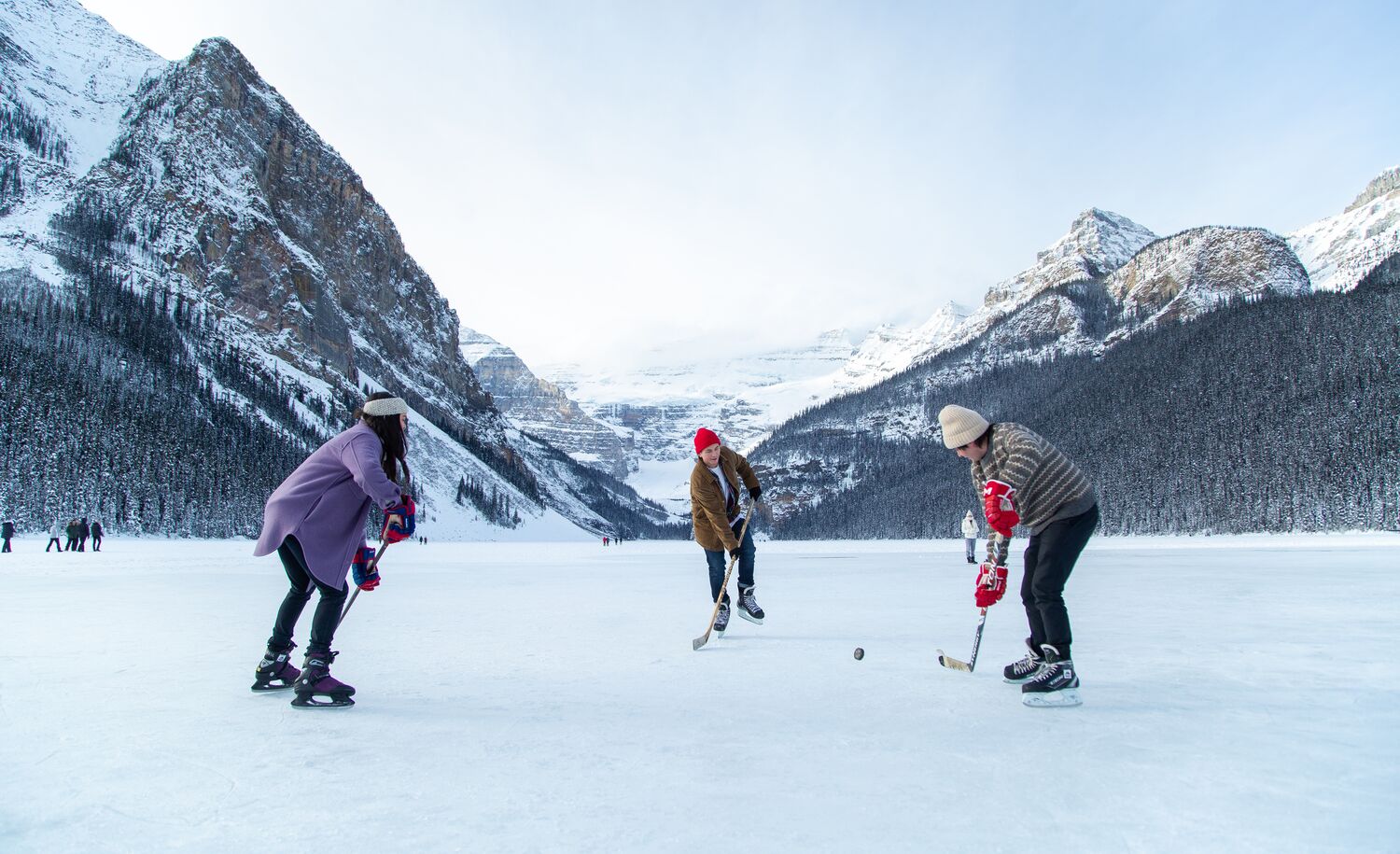 Three people playing hockey on Lake Louise in Banff National Park