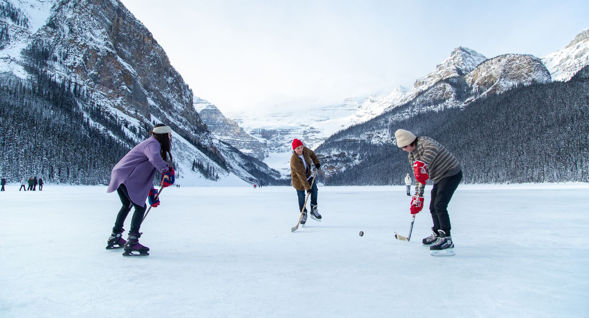 A group of friends playing shinny on Lake Louise in the winter in Banff National Park