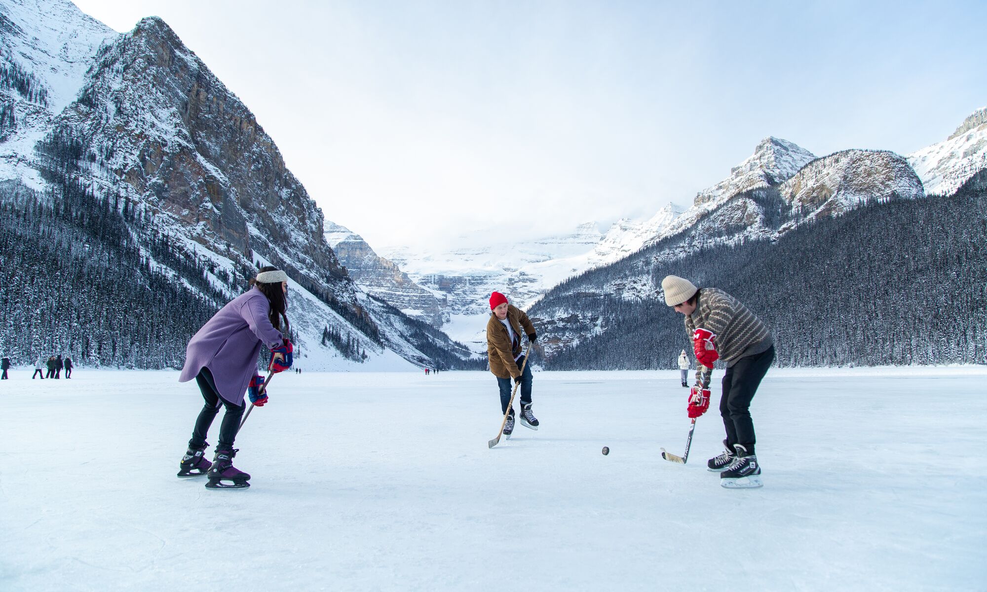 Three people playing hockey on Lake Louise in Banff National Park
