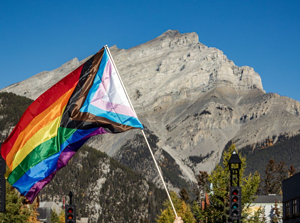 A rainbow pride flag in front of Cascade Mountain in Banff National Park