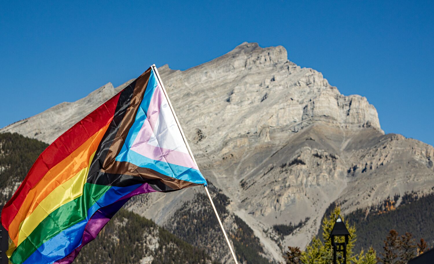 A rainbow pride flag in front of Cascade Mountain in Banff National Park