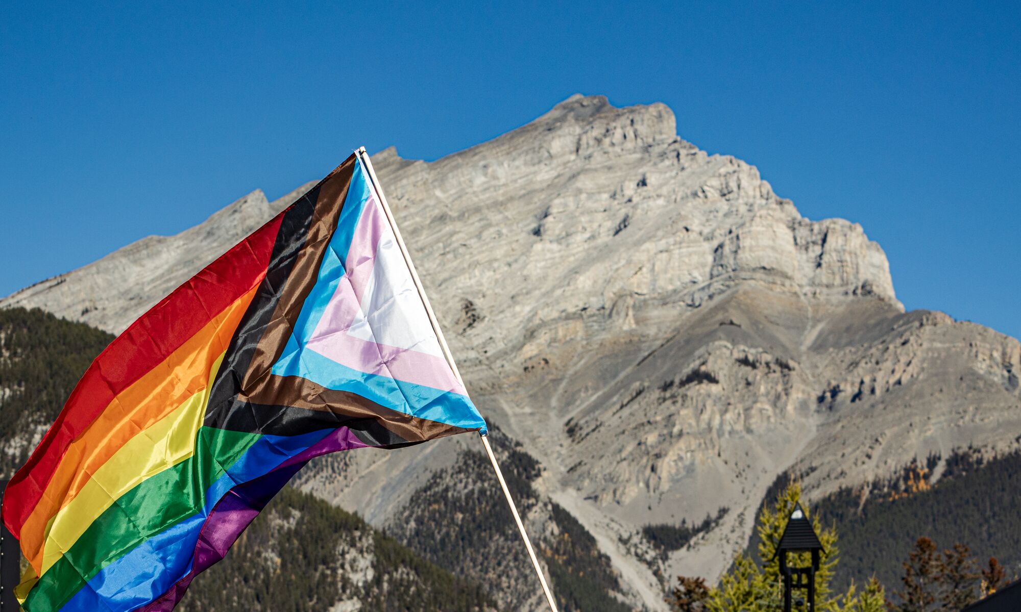 A rainbow pride flag in front of Cascade Mountain in Banff National Park