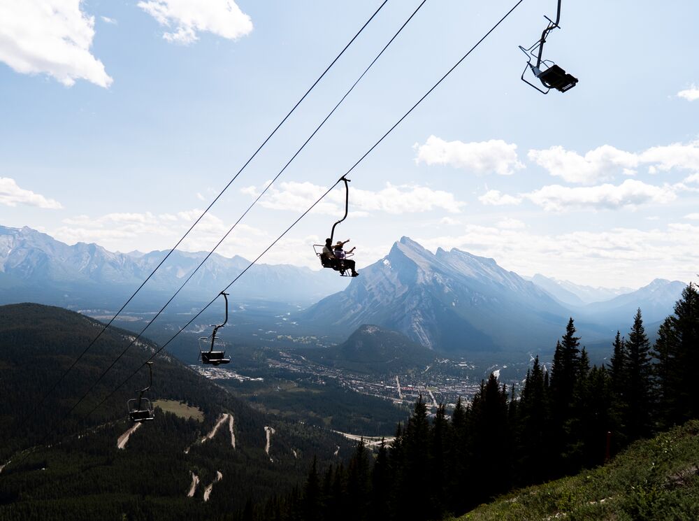 The Mt. Norquay summer sightseeing gondola in front of Mount Rundle on a bluebird day in Banff National Park. 