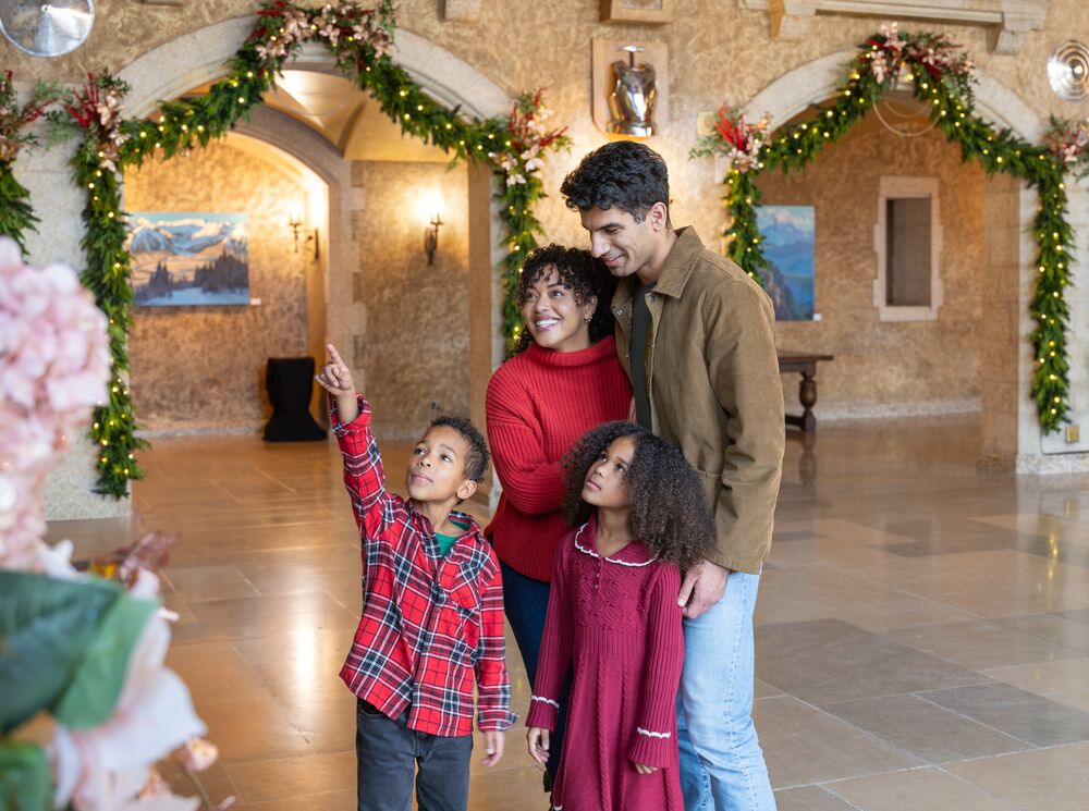 Family and couple standing beneath festive Christmas lights inside the Fairmont Banff Springs during the holiday season in Banff National Park, enjoying one of the must-see Christmas events in the Canadian Rocky Mountains