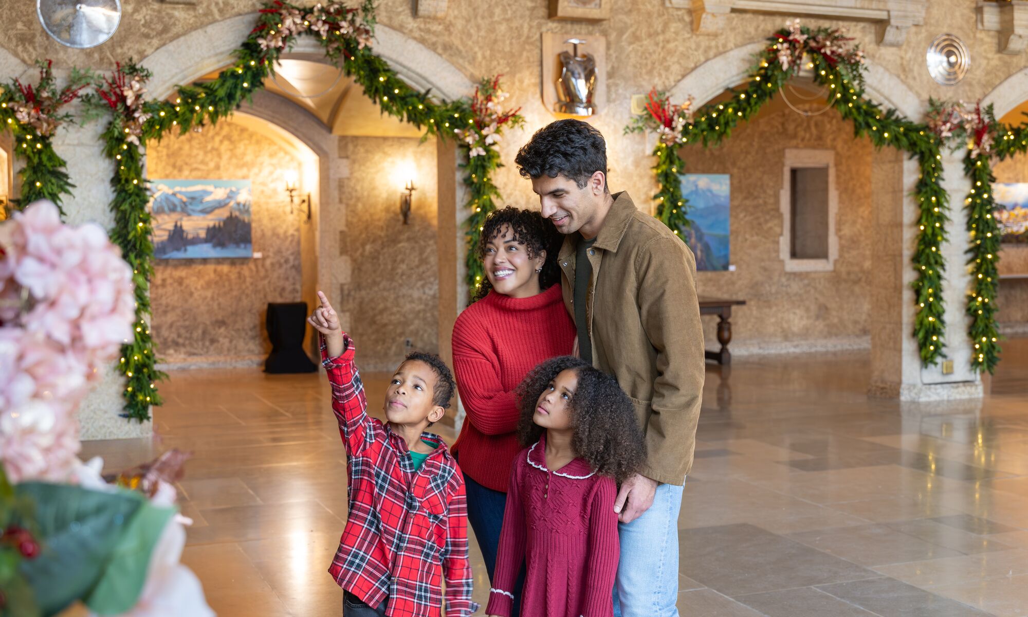 Family and couple standing beneath festive Christmas lights inside the Fairmont Banff Springs during the holiday season in Banff National Park, enjoying one of the must-see Christmas events in the Canadian Rocky Mountains