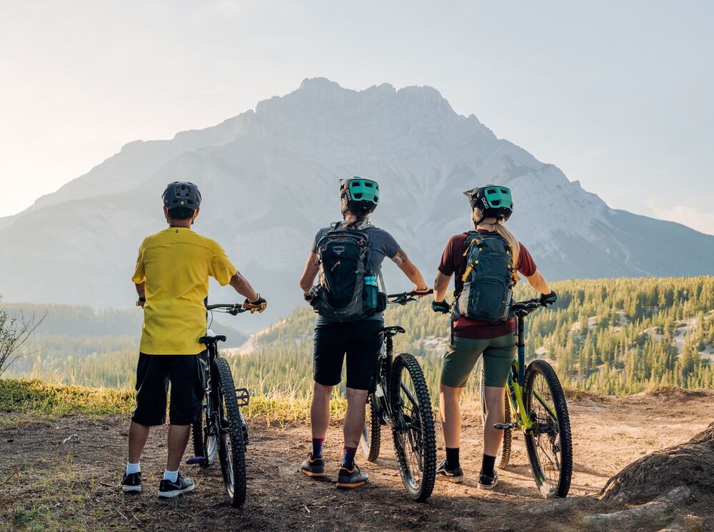 Three people stand looking at Cascade Mountain in Banff National Park during a guided bike tour in Banff.