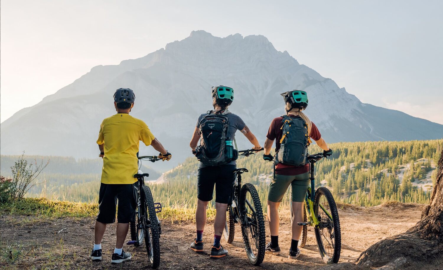 Three people stand looking at Cascade Mountain in Banff National Park during a guided bike tour in Banff.