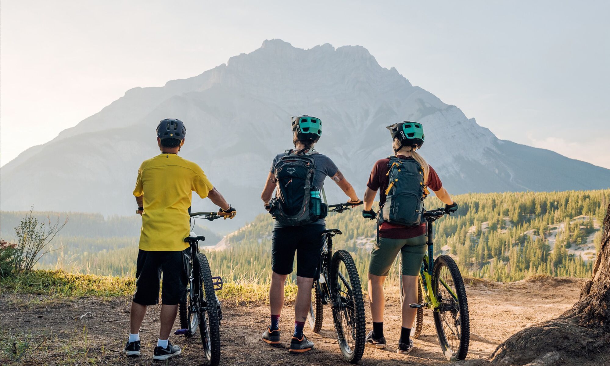 Three people stand looking at Cascade Mountain in Banff National Park during a guided bike tour in Banff.