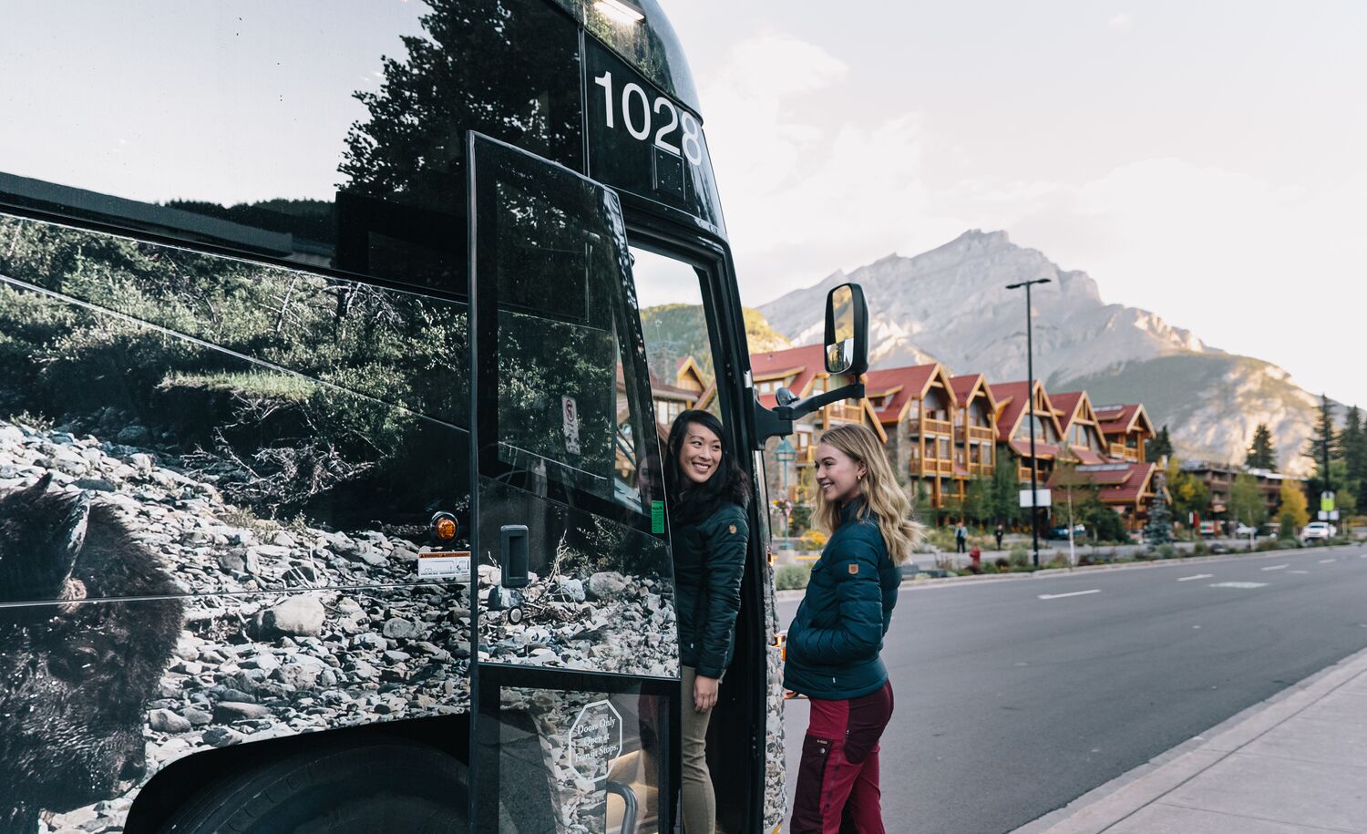 Two people get on a Roam Transit bus in the summer, heading to hike in Lake Louise.