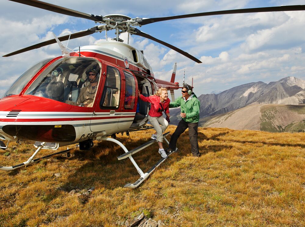 A woman gets off a helicopter on a mountain to go heli-hiking near Banff National Park.