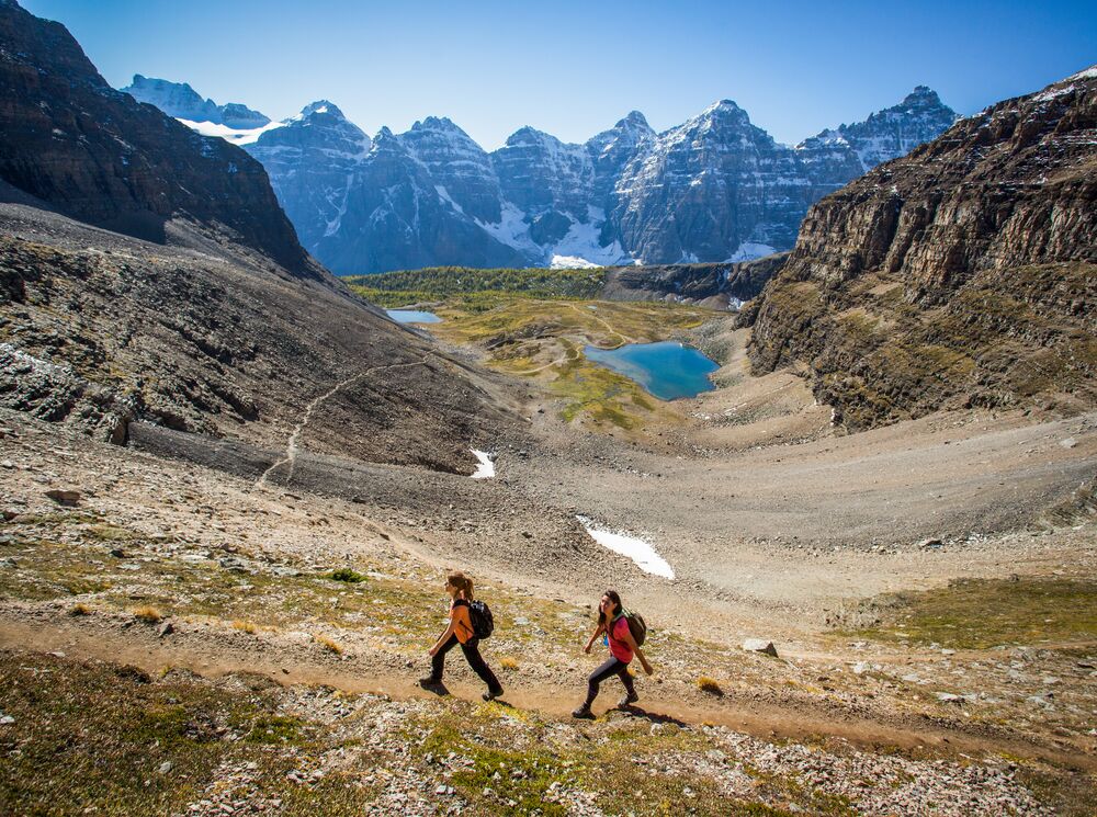 Two women walk up Sentinel Pass above Larch Valley, one of the best hikes to do at Moraine Lake in Banff National Park.