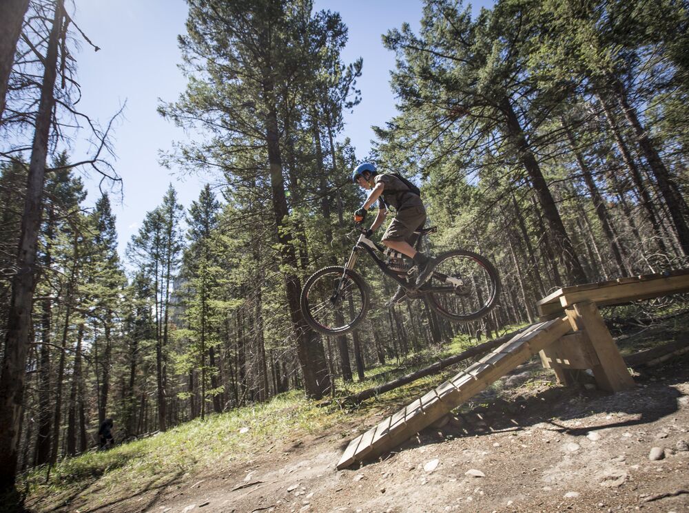 A mountain biker hits a jump on the Tunnel Mountain Trails in Banff National Park.