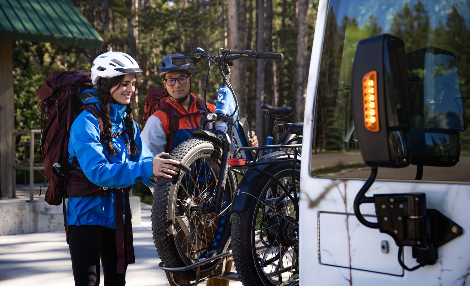 Two people mount bikes on the front of a Roam Transit bus to get to their mountain bike route in Banff National Park.