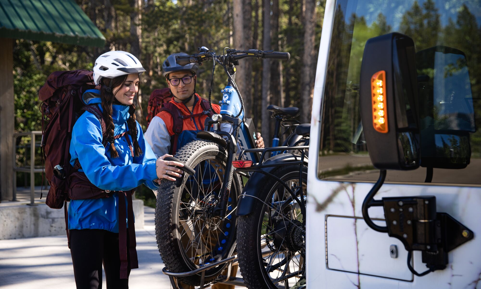 Two people mount bikes on the front of a Roam Transit bus to get to their mountain bike route in Banff National Park.