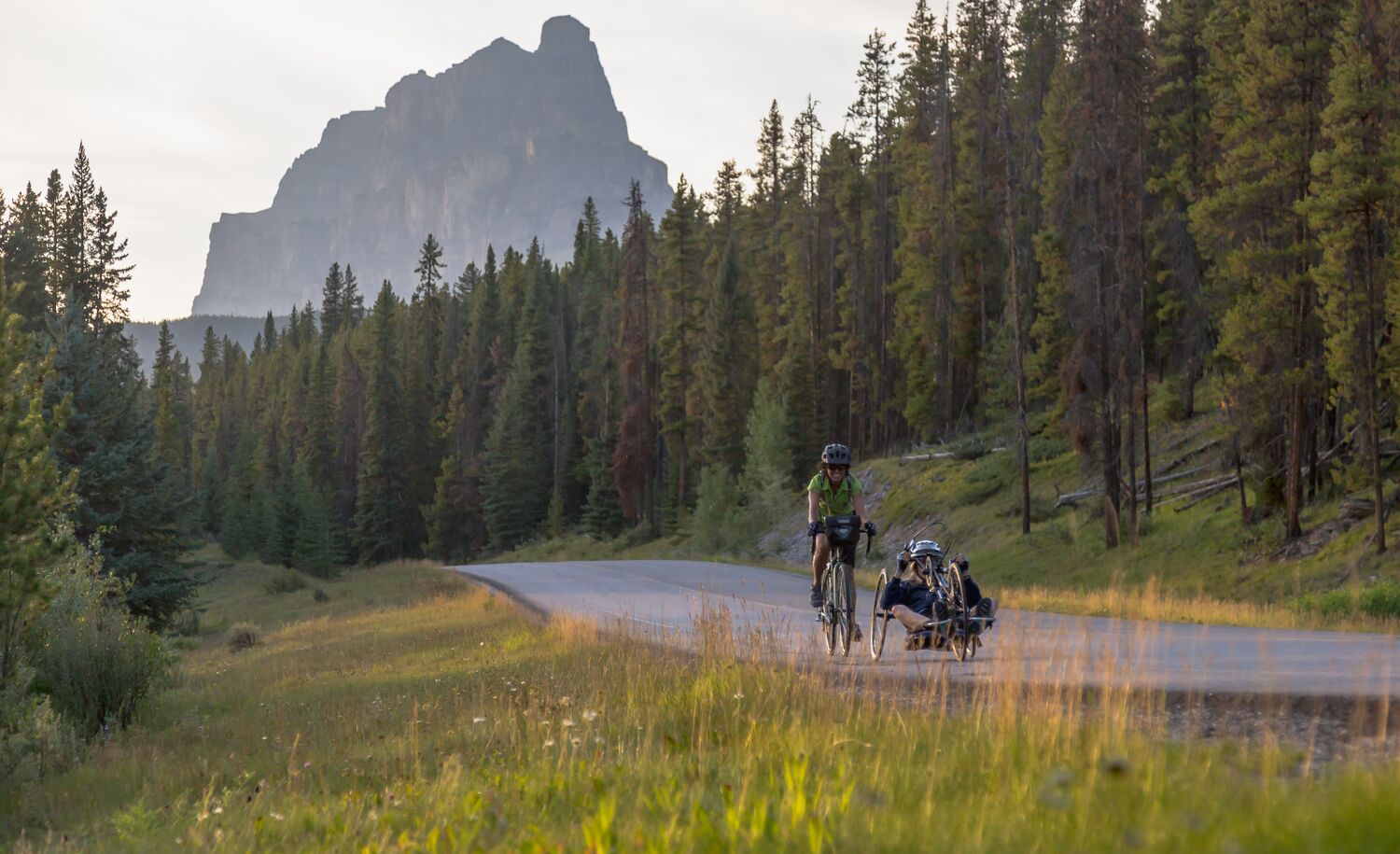 Two cyclists on a summer day ride the Bow Valley Parkway in Banff National Park.