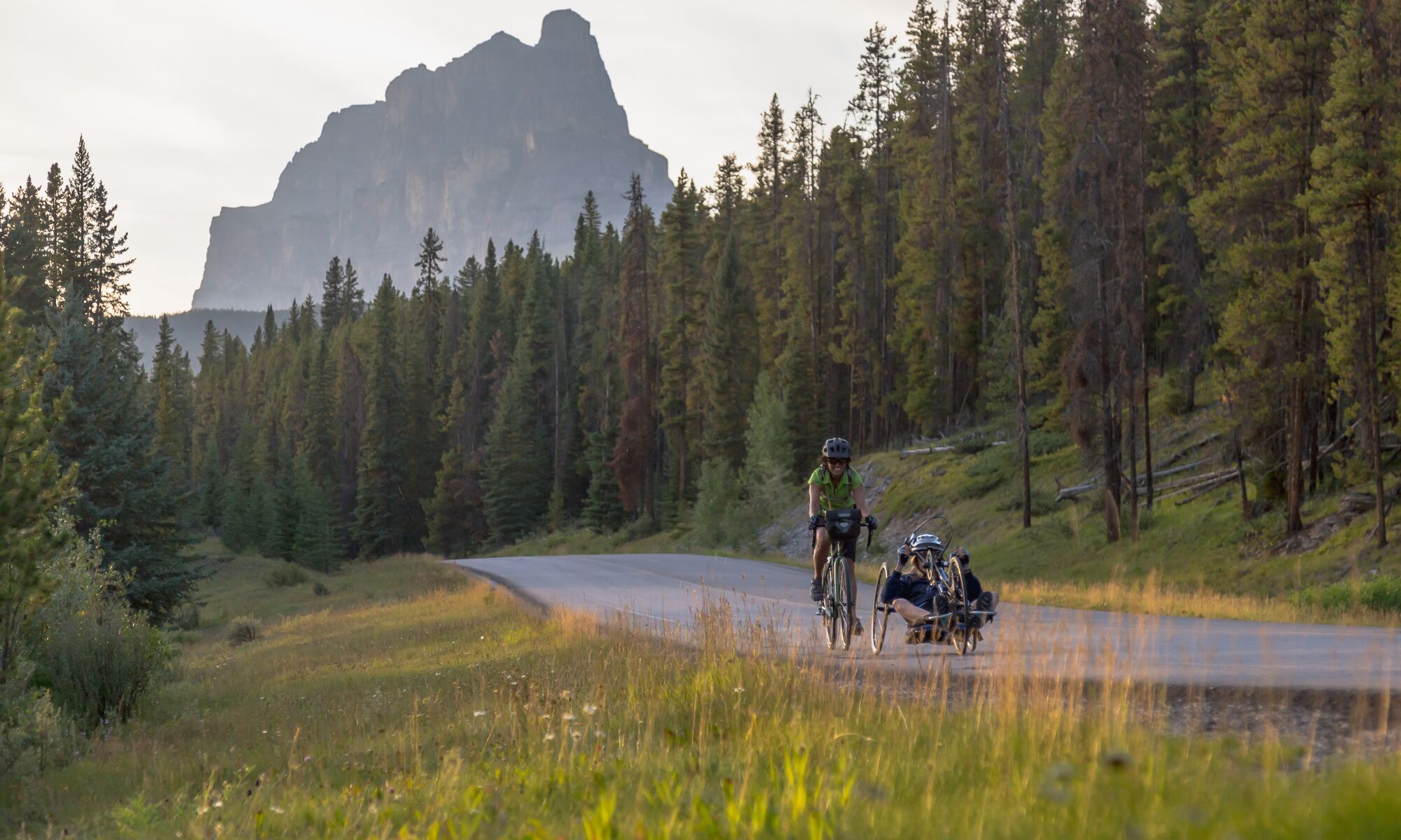 Two cyclists on a summer day ride the Bow Valley Parkway in Banff National Park.