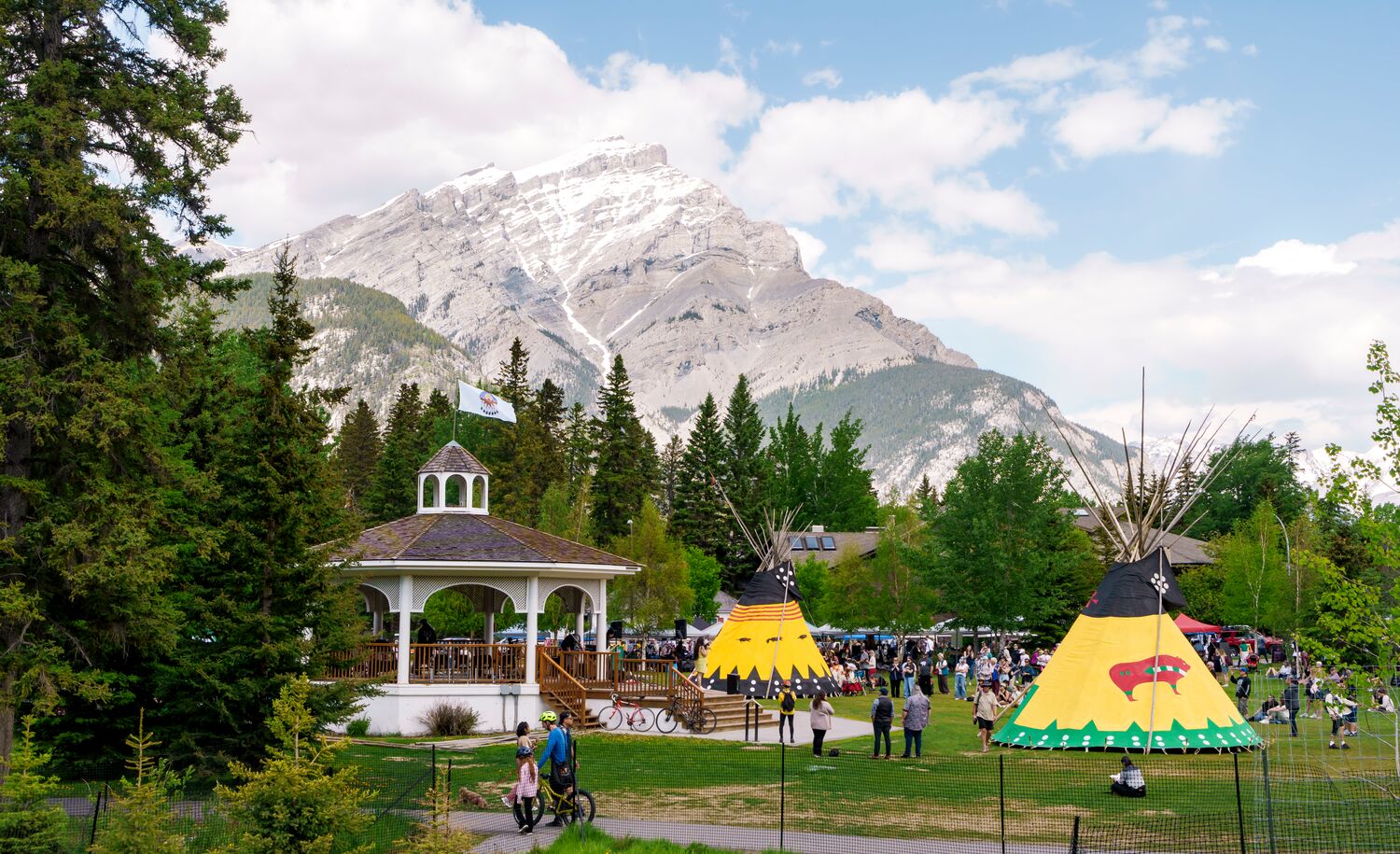 Two teepees and a gazebo in Central Park in the Banff townsite with Cascade Mountain behind them on a summer day in Banff National Park.