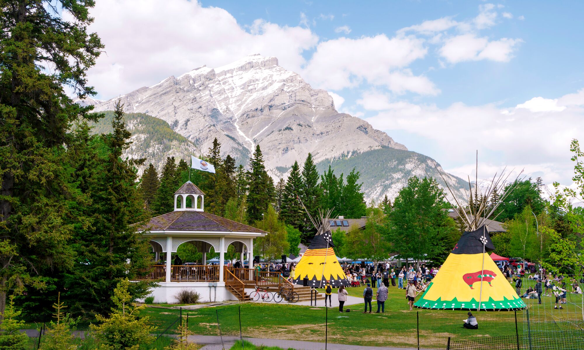Two teepees and a gazebo in Central Park in the Banff townsite with Cascade Mountain behind them on a summer day in Banff National Park.