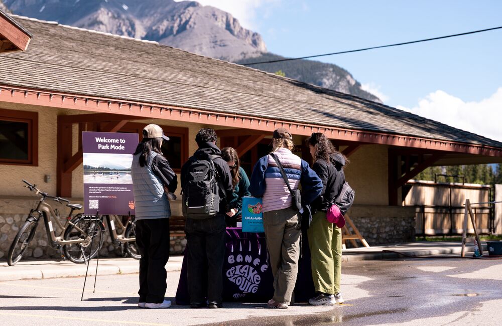 Visitors learn about Park Mode and responsible travel at an activation event outside the Banff Train Station in Banff National Park.
