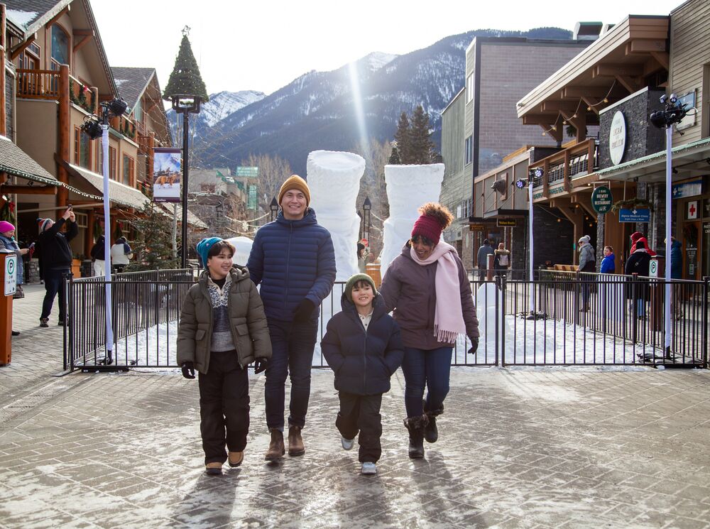 A family of four walking in Banff National Park with a snow sculpture in the background