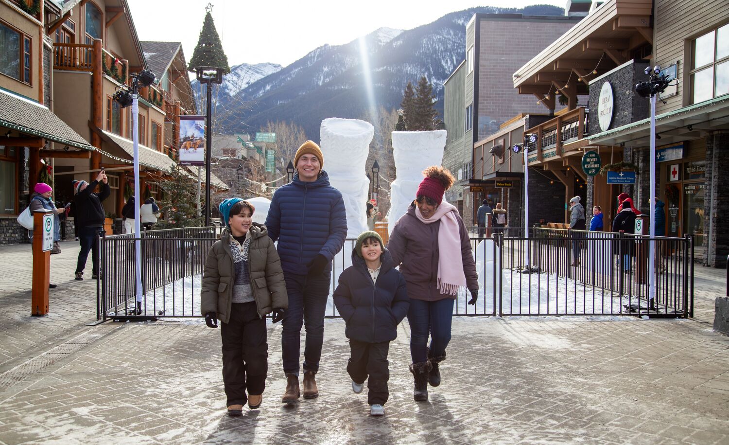 A family of four walking in Banff National Park with a snow sculpture in the background