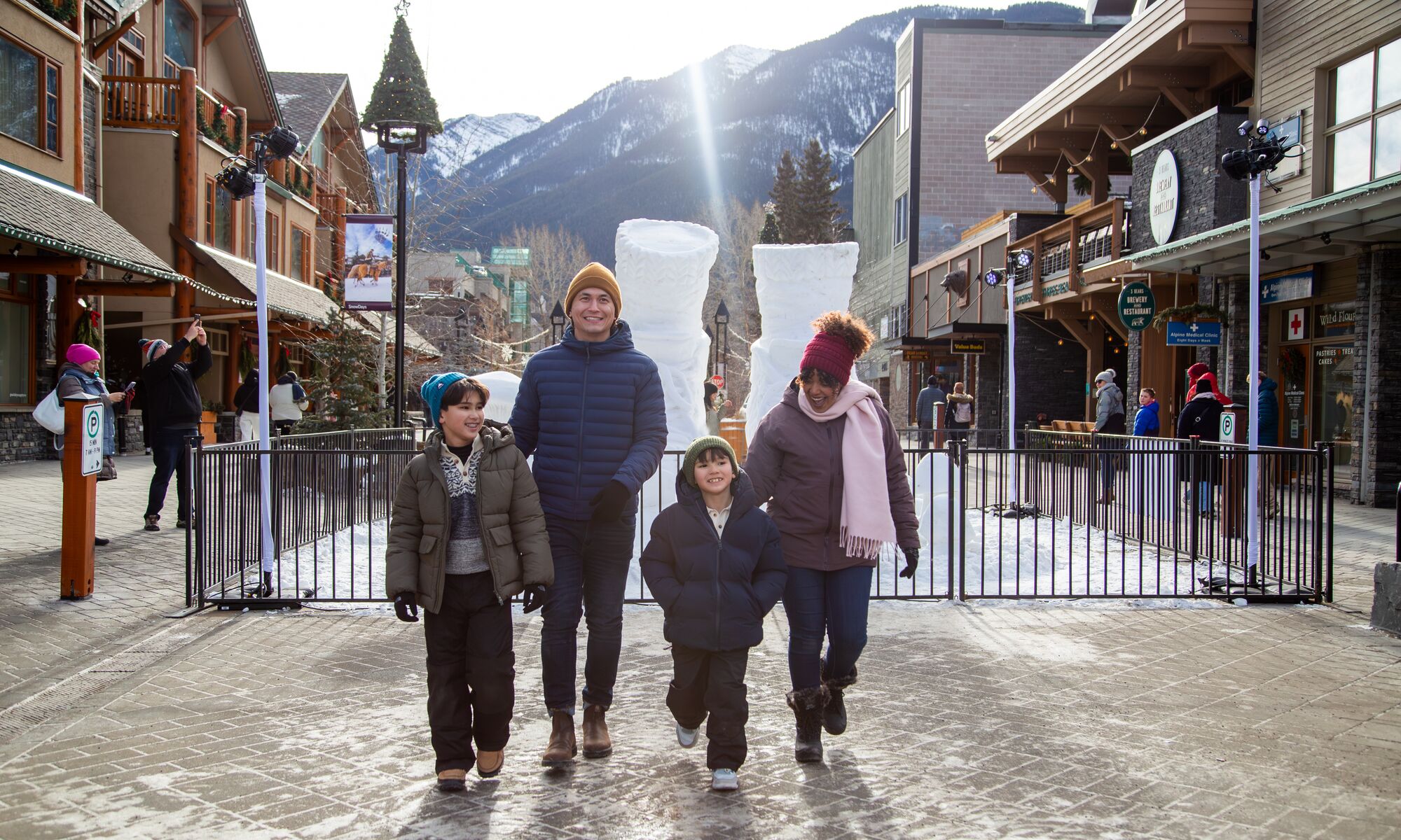 A family of four walking in Banff National Park with a snow sculpture in the background