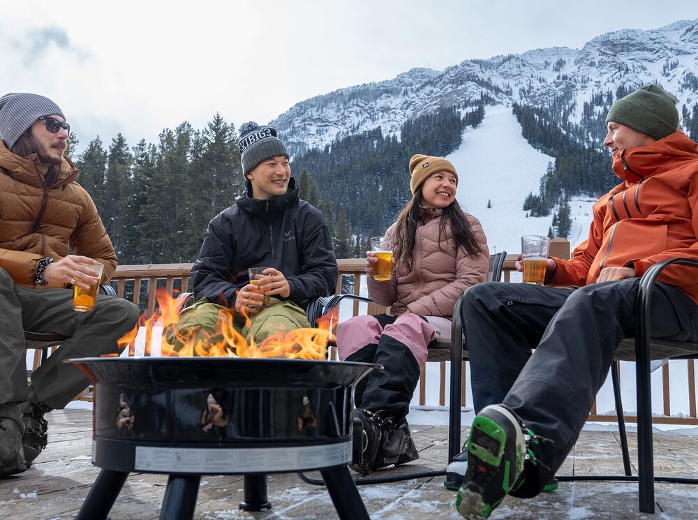 Four people on an outdoor patio at the Mt. Norquay ski area in Banff National Park