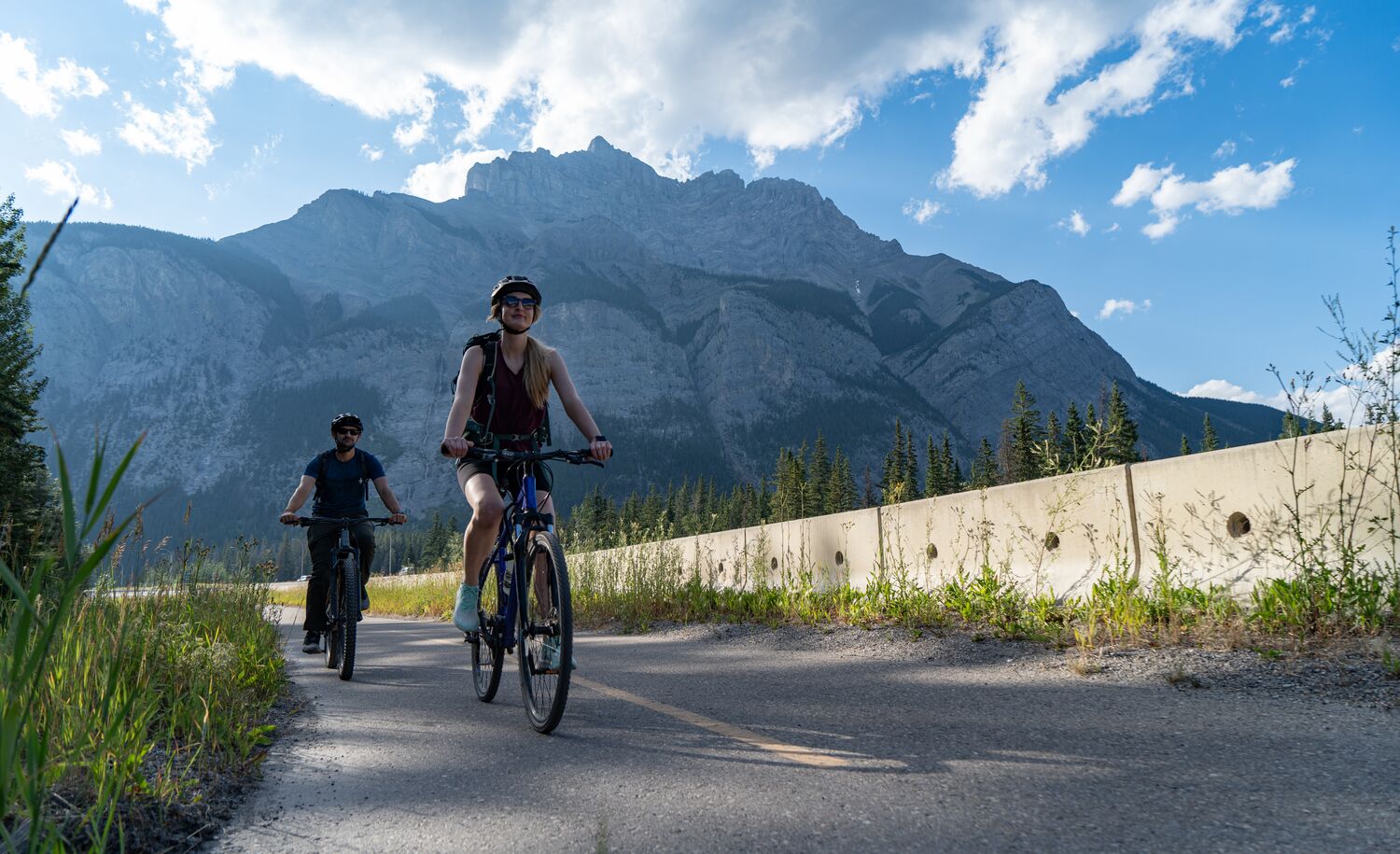 Two people bike along the Legacy Trail outside the Banff townsite on a bluebird evening in Banff National Park.