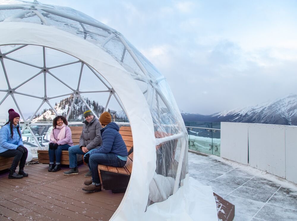 Four people on top of the Banff gondola in winter in Banff National Park