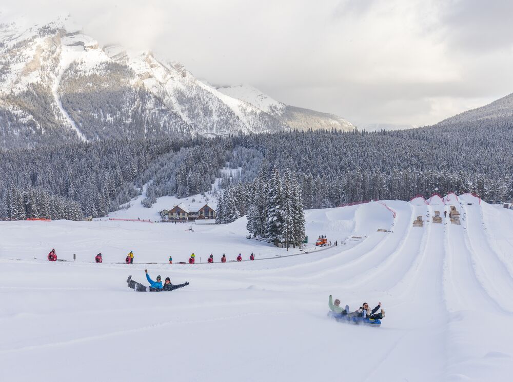 Two groups of people tubing down a hill at Mount Norquay in Banff National Park