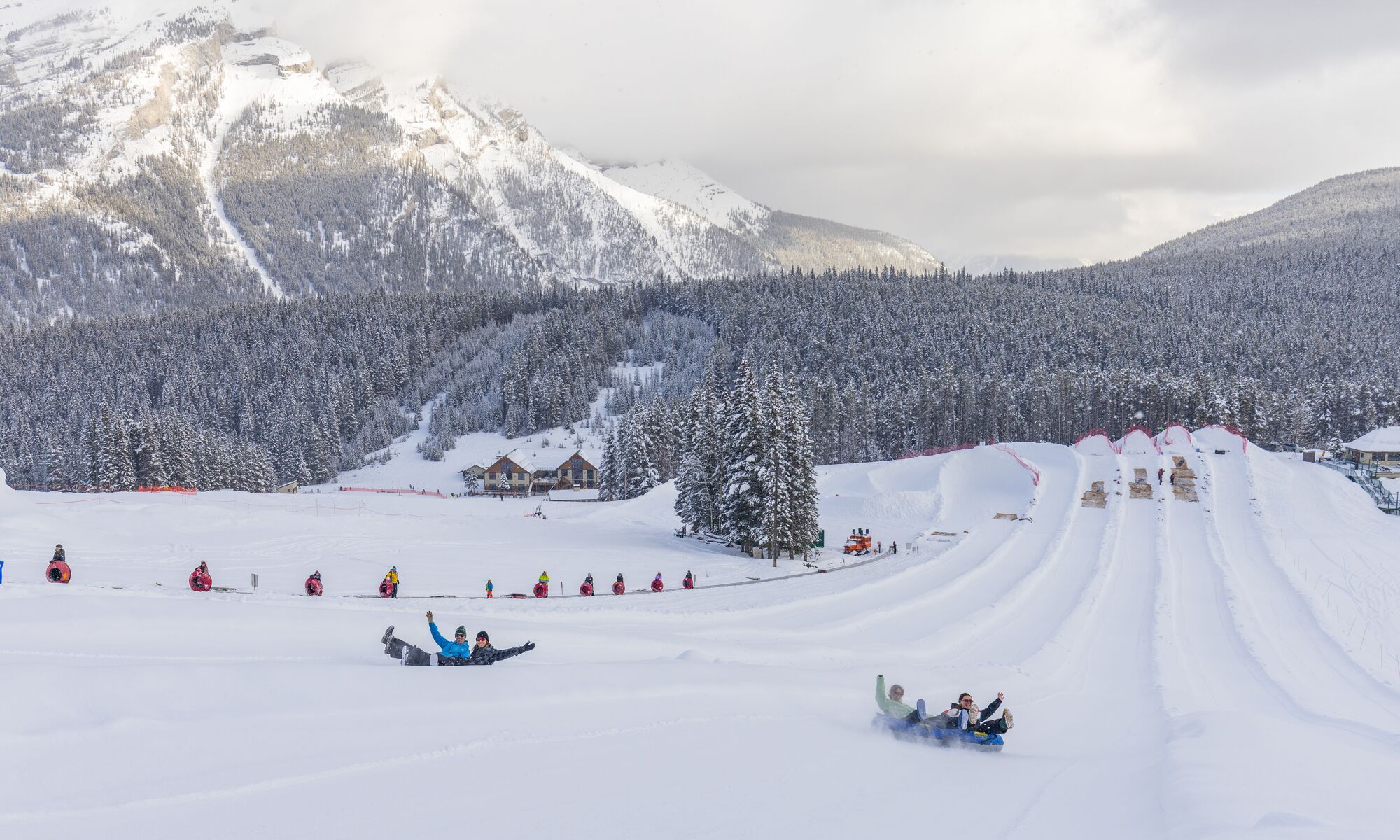 Two groups of people tubing down a hill at Mount Norquay in Banff National Park