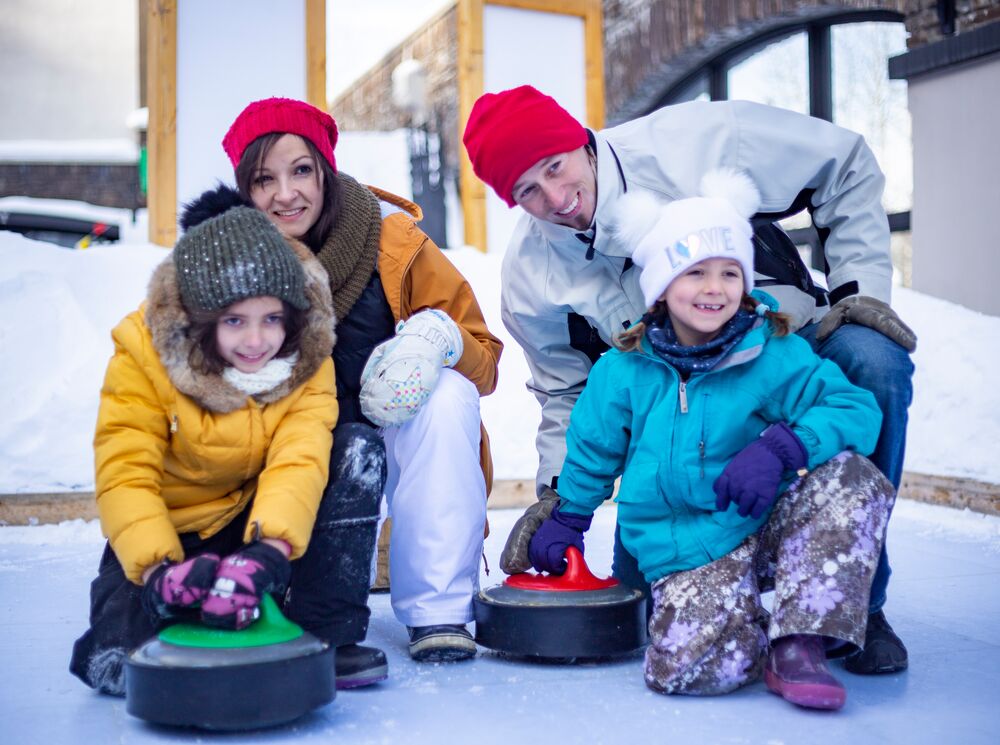 A family of four playing curing at the winter carnival in Banff National Park
