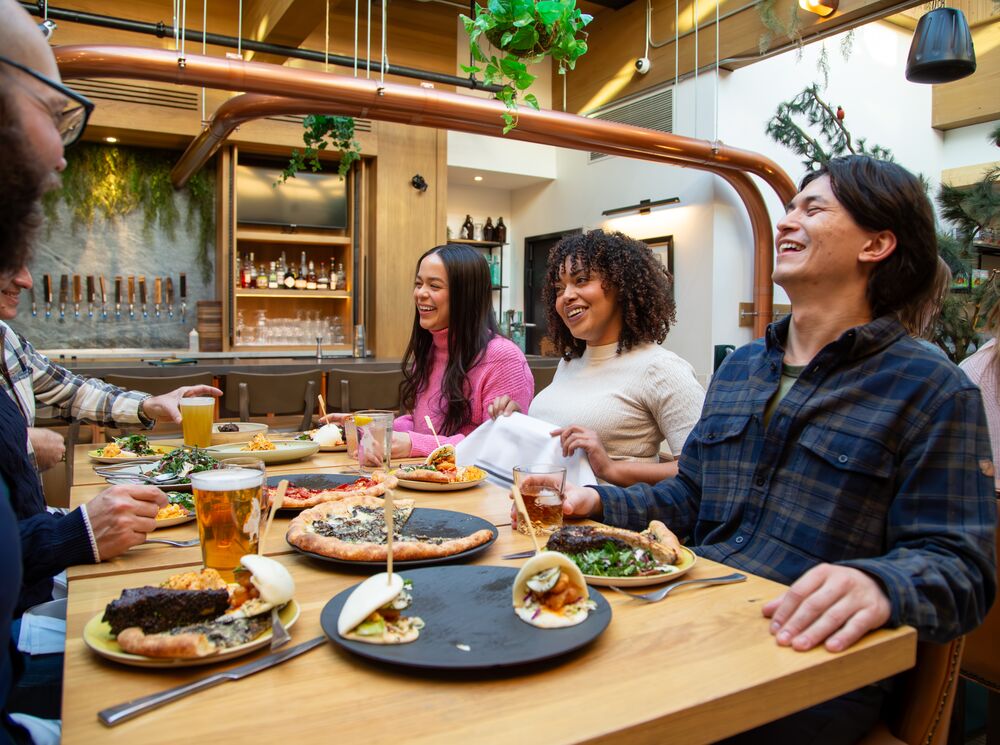 A group of people enjoy a family-style meal while sitting around a table at Three Bears Restaurant in Banff National Park.