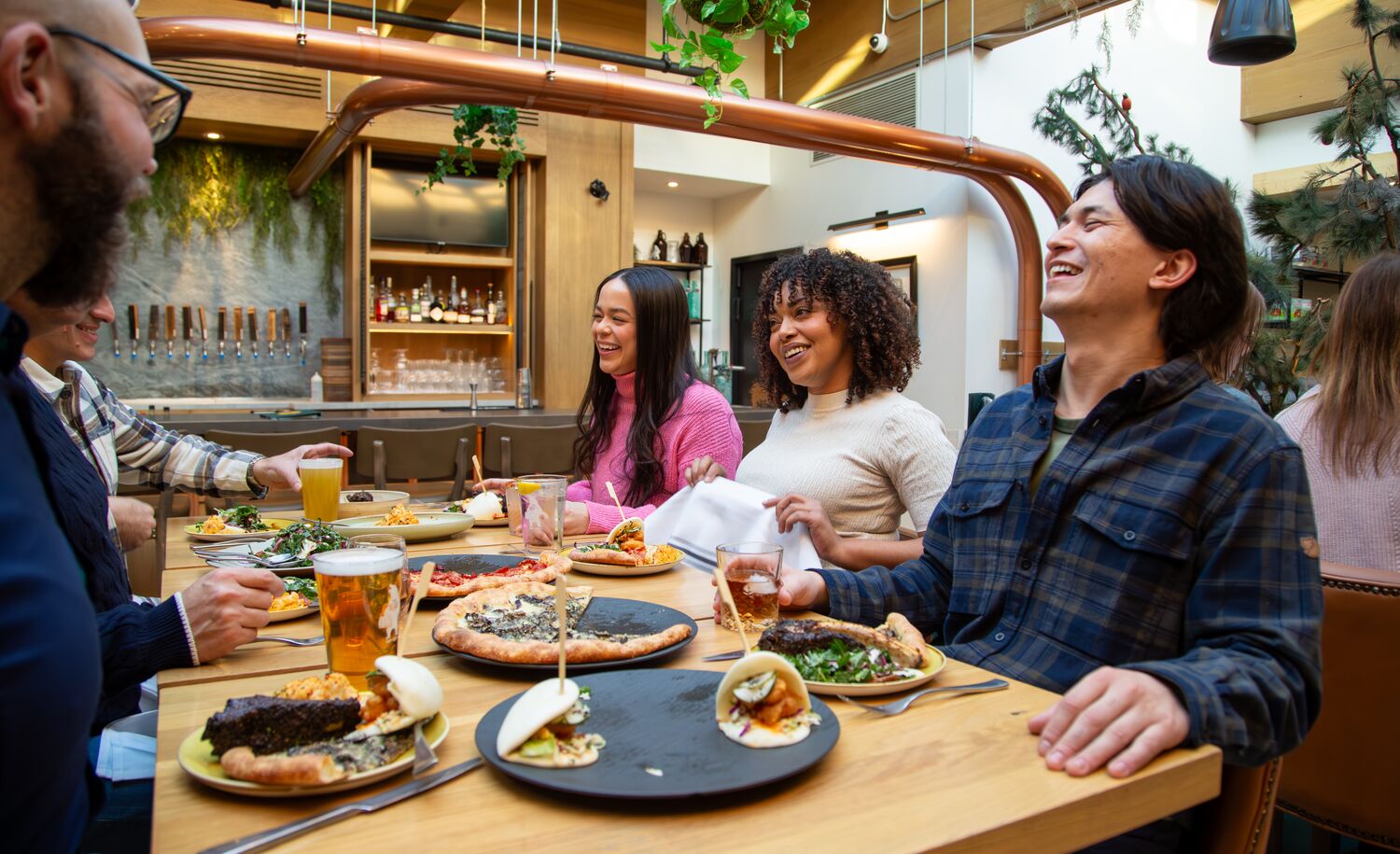 A group of people enjoy a family-style meal while sitting around a table at Three Bears Restaurant in Banff National Park.
