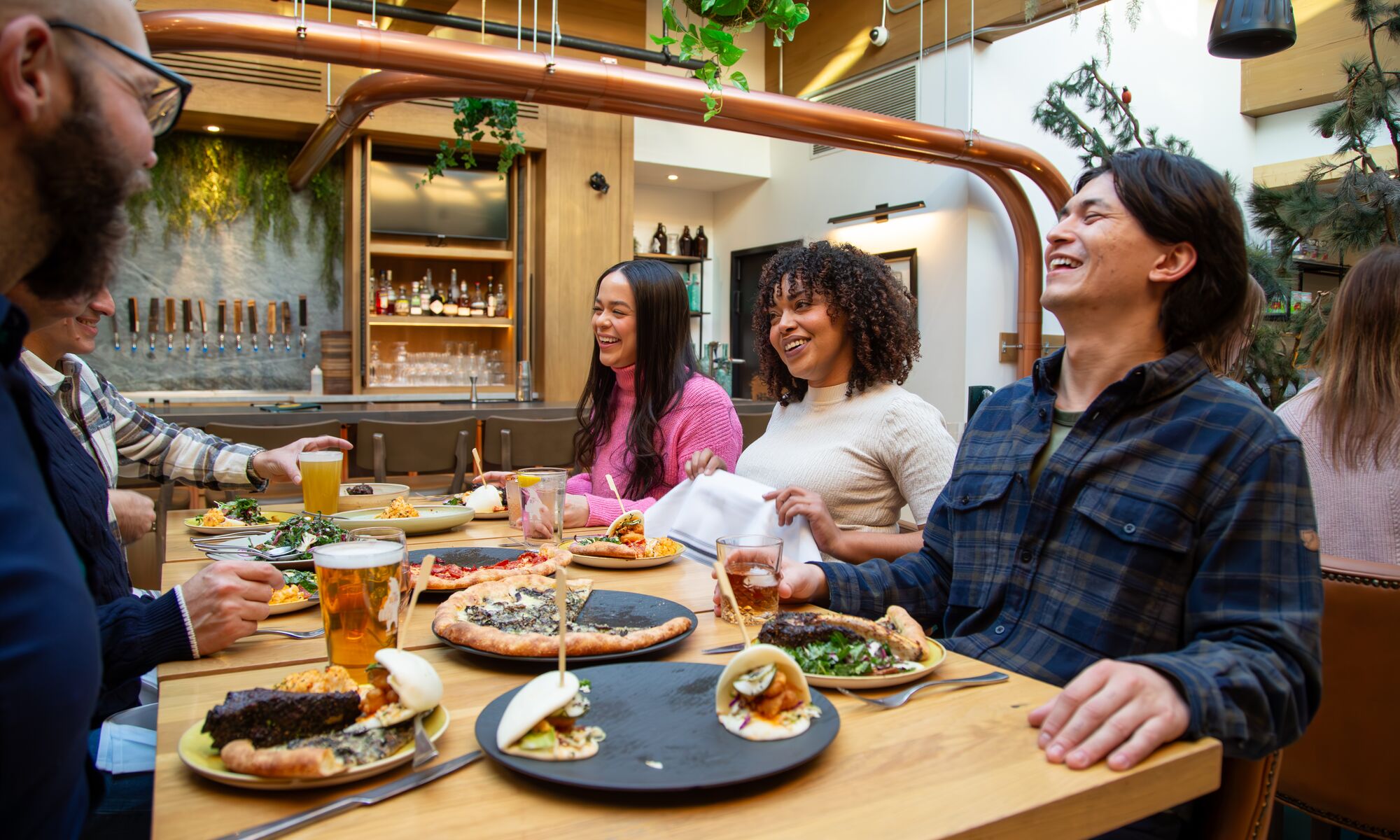 A group of people enjoy a family-style meal while sitting around a table at Three Bears Restaurant in Banff National Park.