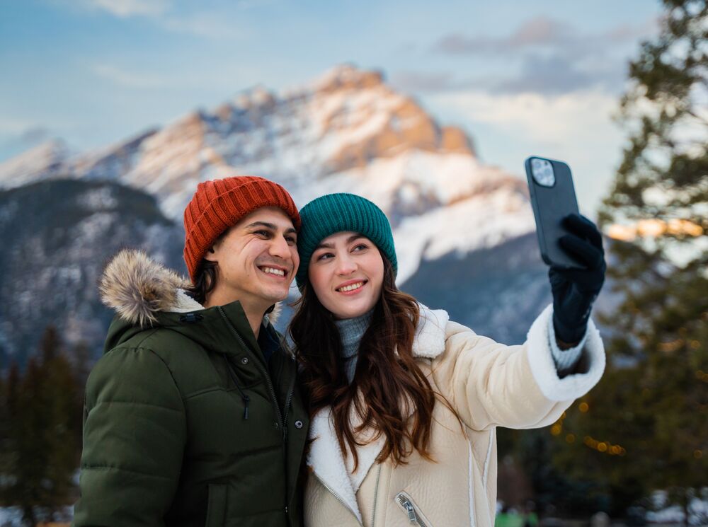 A couple taking a photo with Cascade Mountain in the back in Banff National Park
