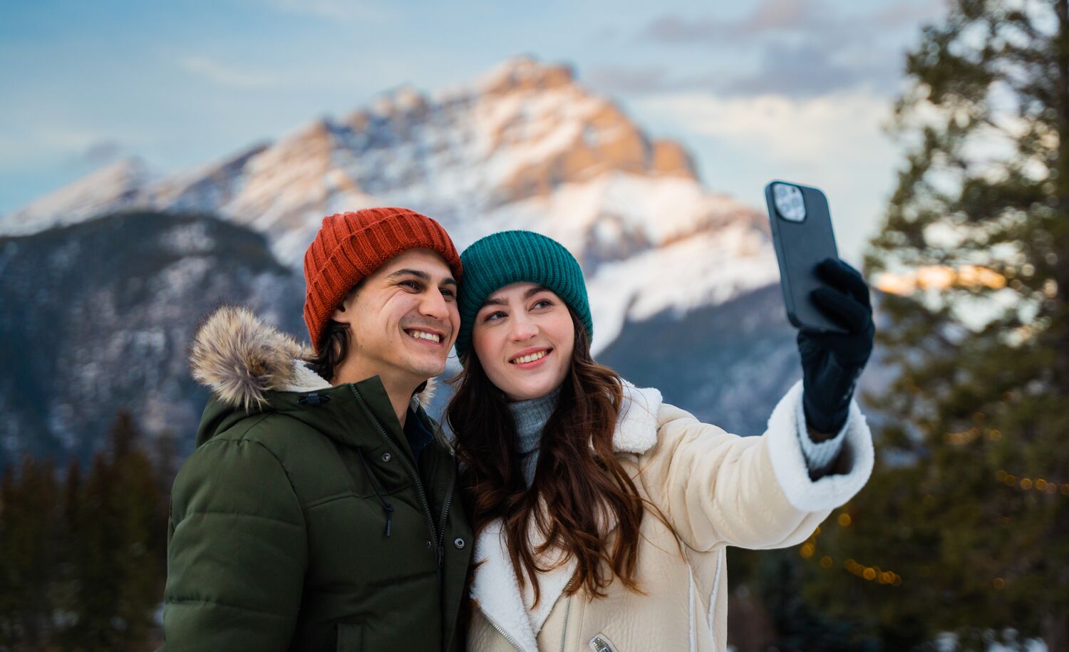 A couple taking a photo with Cascade Mountain in the back in Banff National Park