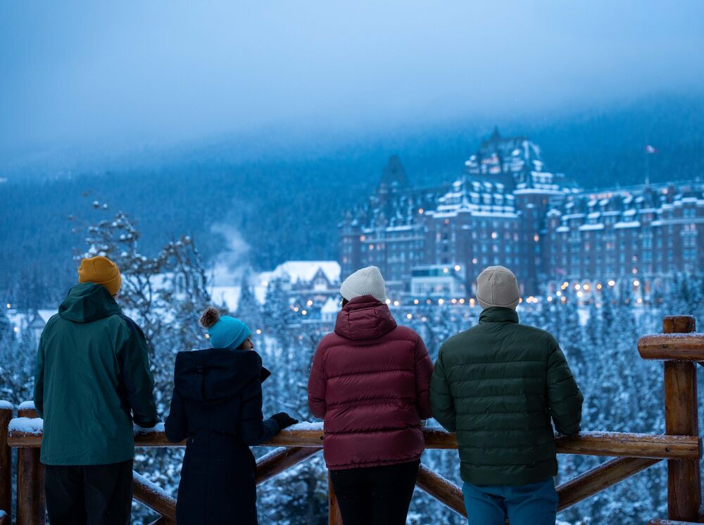 Four people standing at Surprise Corner looking at the Banff Springs Hotel in Banff National Park