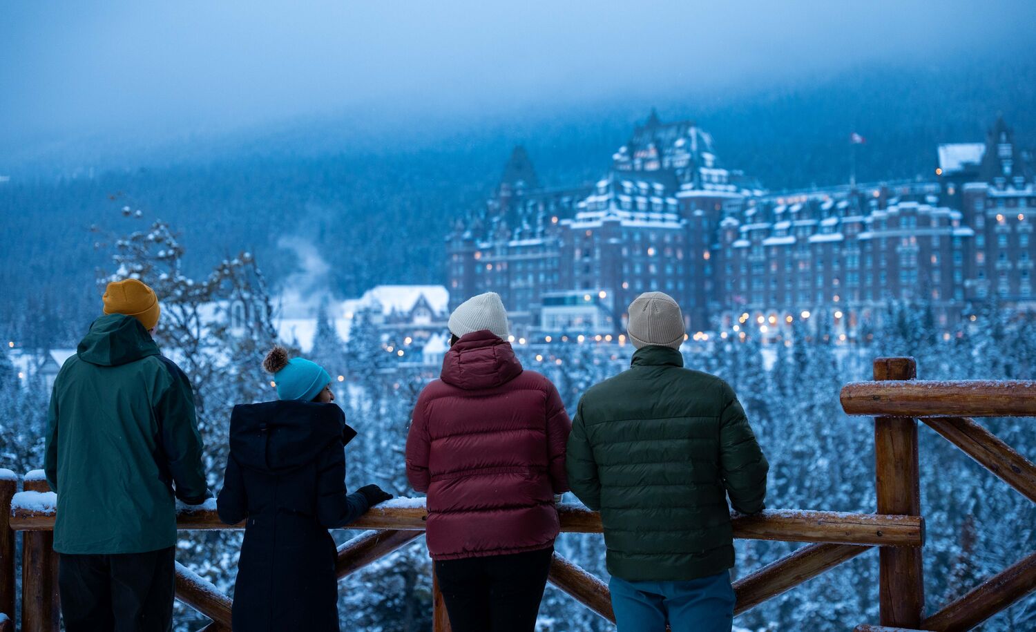 Four people standing at Surprise Corner looking at the Banff Springs Hotel in Banff National Park
