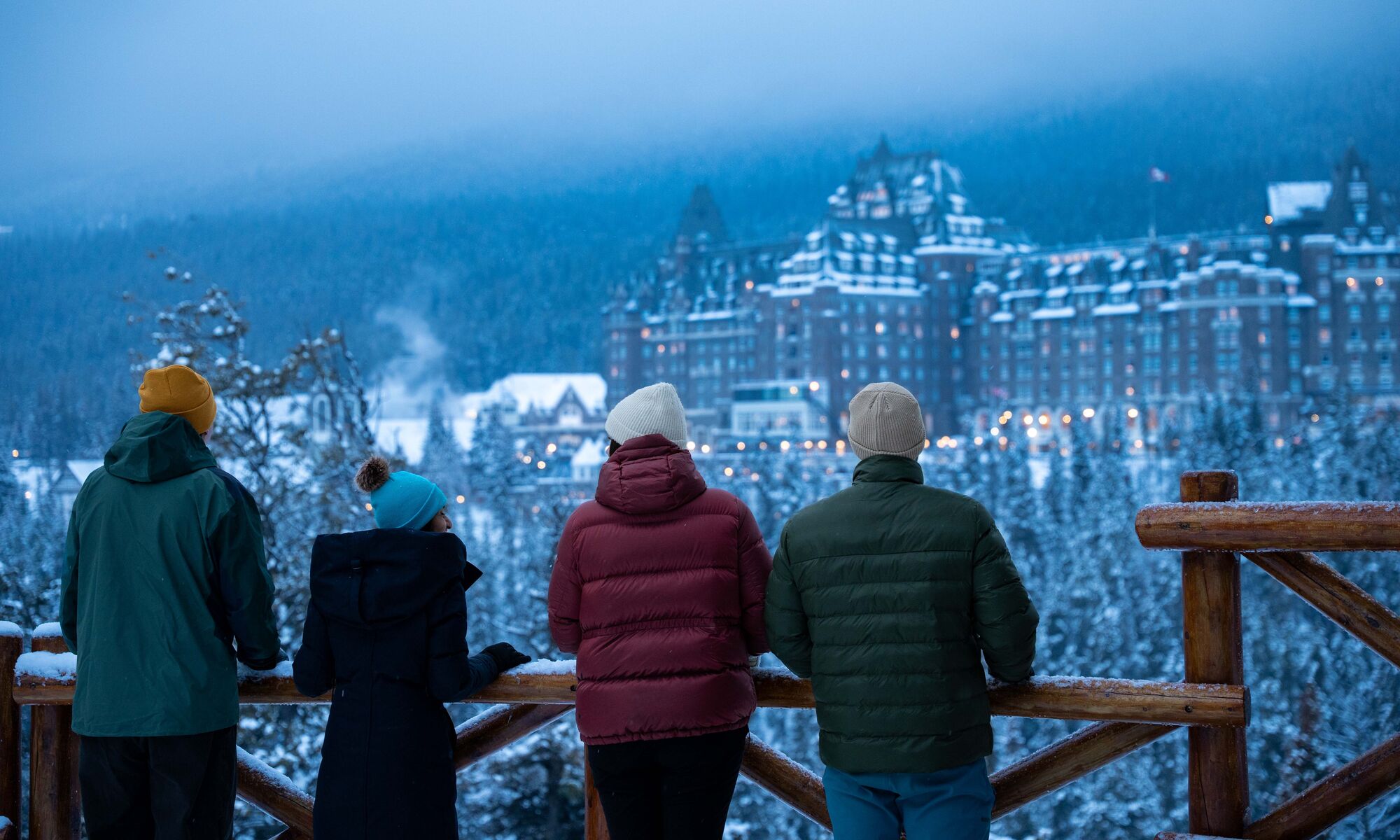 Four people standing at Surprise Corner looking at the Banff Springs Hotel in Banff National Park