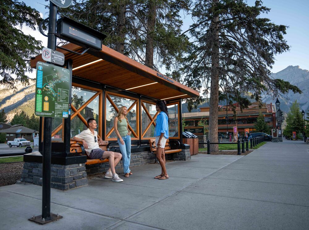 Three people waiting at a Roam Transit bus stop in Banff National Park