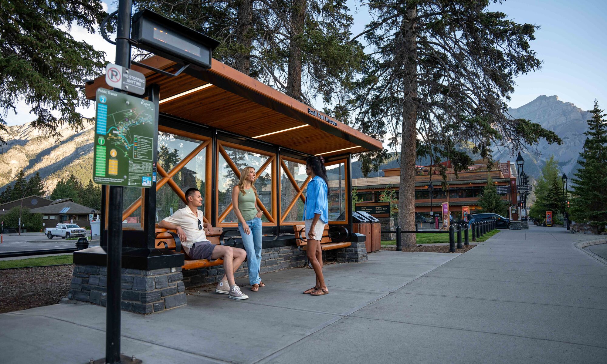 Three people waiting at a Roam Transit bus stop in Banff National Park