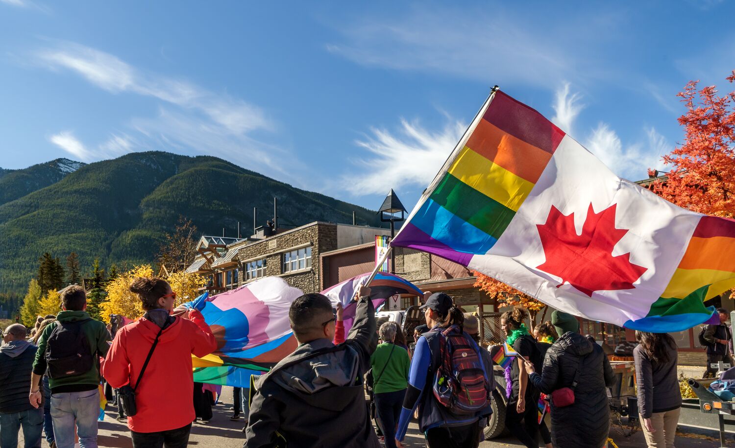 2SLGBTQIA+ community members, visitors, allies, and locals walk along Banff Avenue with a Canadian Pride flag during the Banff Pride Festival in Banff National Park, celebrating inclusion, diversity, and community at one of Canada's premier Pride events.