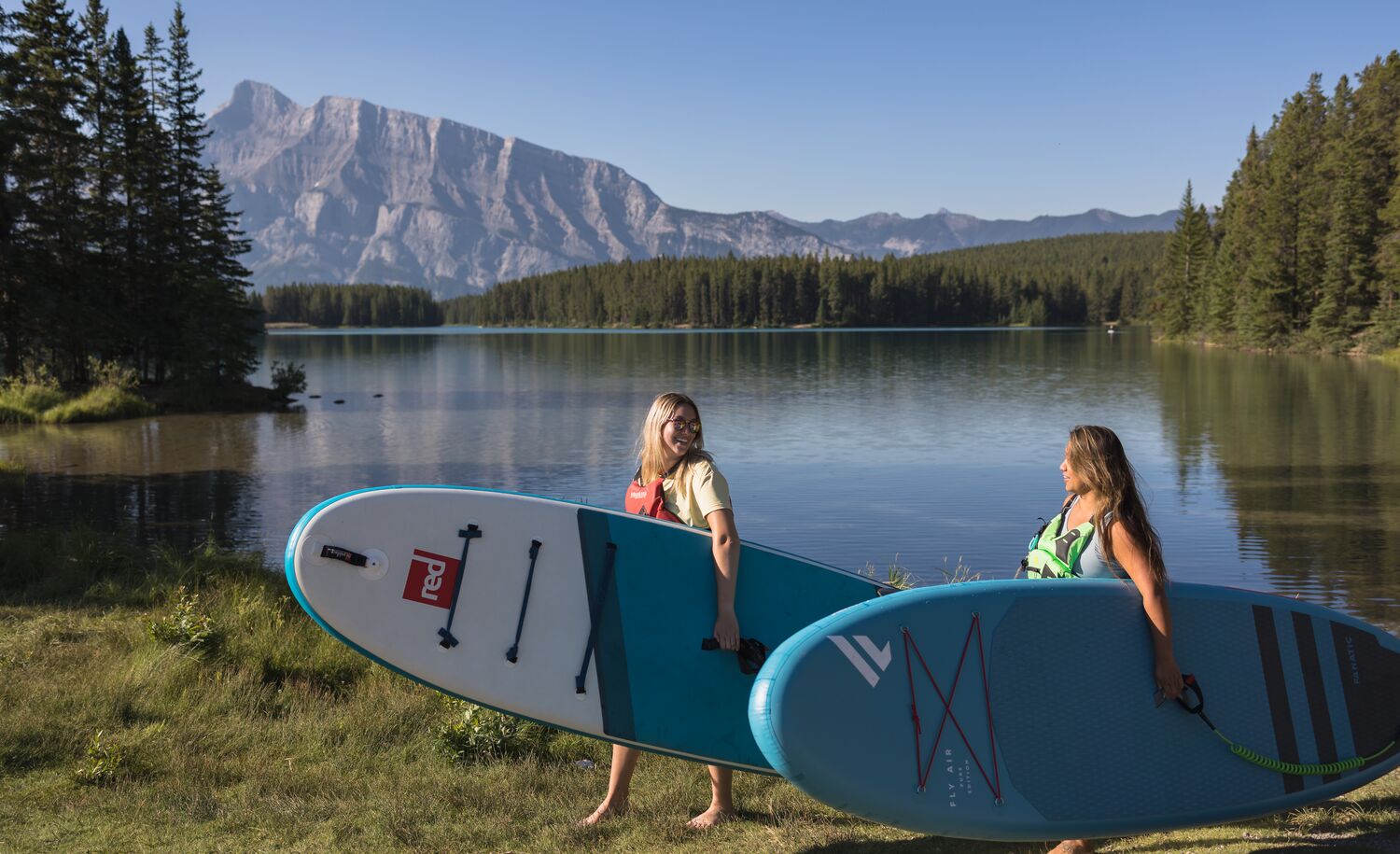 Two people carrying their paddle boards from Two Jack Lake in Banff National Park