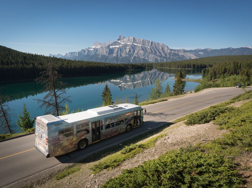 A Roam Transit bus driving past Two Jack Lake in Banff National Park