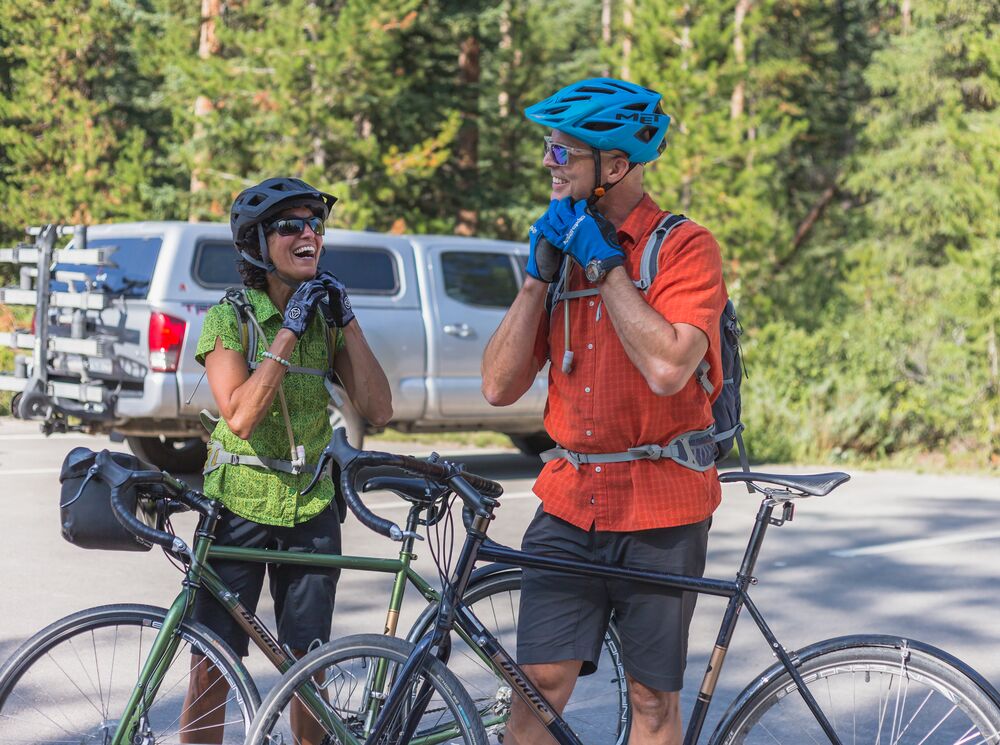 Two cyclists buckle up their helmets before heading out biking in Banff National Park.