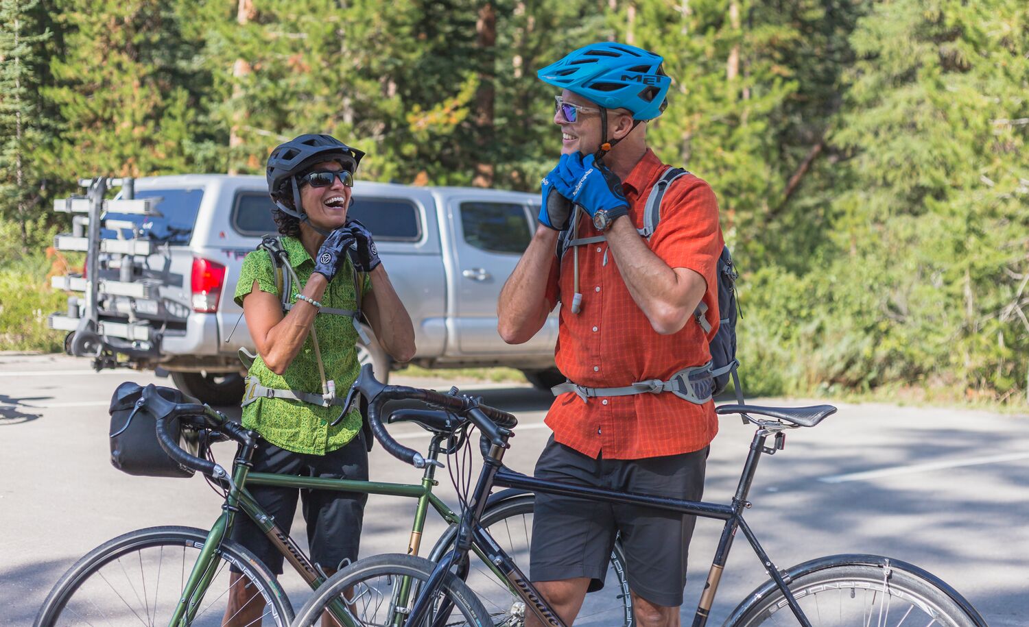 Two cyclists buckle up their helmets before heading out biking in Banff National Park.